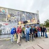 The former workers at the Albion Malleable Iron Company stand proudly in front of the mural that shows scenes of where they once worked.