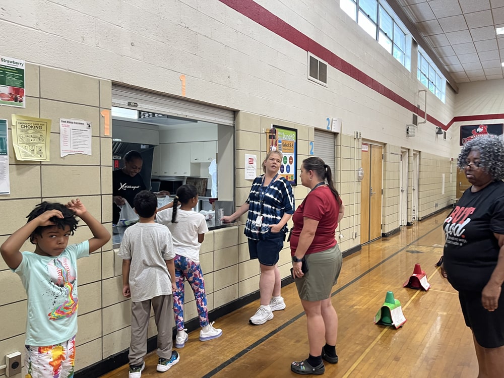 Children line up for free lunch inside Harrington Elementary School during the Meet Up and Eat Up program. Staff and volunteers from Marshall Public Schools help make the experience smooth and friendly for all participants.
