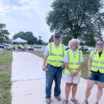 Terry and Dana Anderla, longtime volunteers, stand with Amanda Cheladyn, manager of the Community Table of Albion at the new distribution location at the high school. Volunteers in high-visibility vests help guide traffic and distribute food to residents who come to get the food.